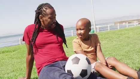 video of happy african american father and son having fun with ball outdoors
