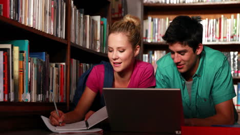 estudiantes acostados en el piso de la biblioteca estudiando juntos