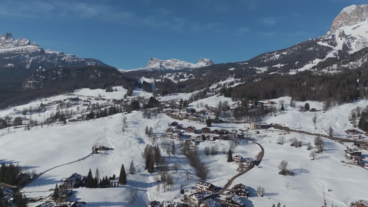 Alpine town and surrounding Dolomites mountains under a blue sky. Cortina d'Ampezzo, Italy. Drone, aerial view