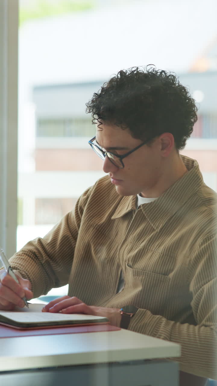 Ung mann skriver notater i en notatbok ved et skrivebord