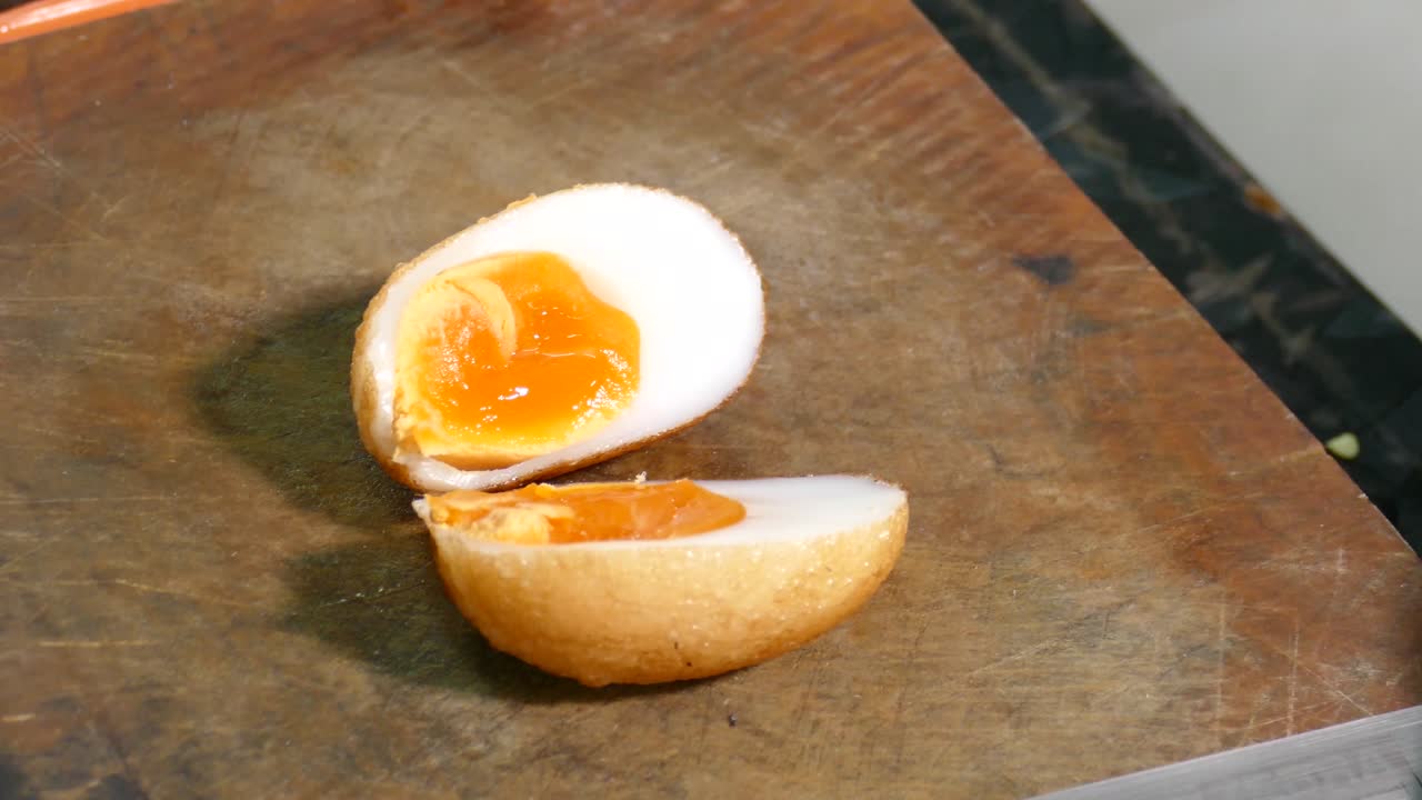 Close-up Footage of Chef Cutting Whole Deep Fried Egg into Half to Show Juicy Yolk inside