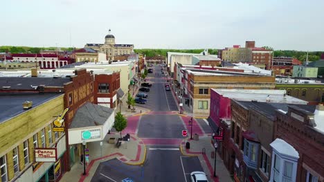 a lovely aerial over a main street in small town usa ends with two kids skateboarding down the empty boulevard