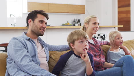 Family-Sitting-On-Sofa-In-Lounge-Watching-Television-Together