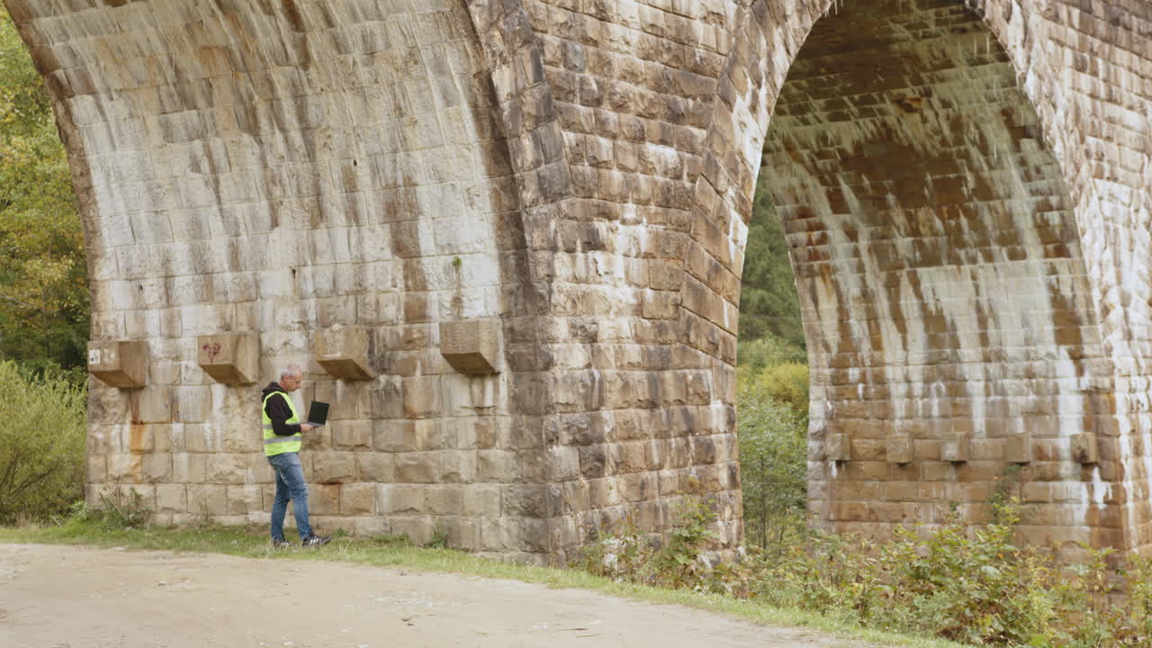 ingeniero inspeccionando el puente de arco de piedra