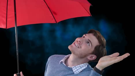 Smiling-man-under-red-umbrella-checking-for-rain-with-hand-out,-on-black-background