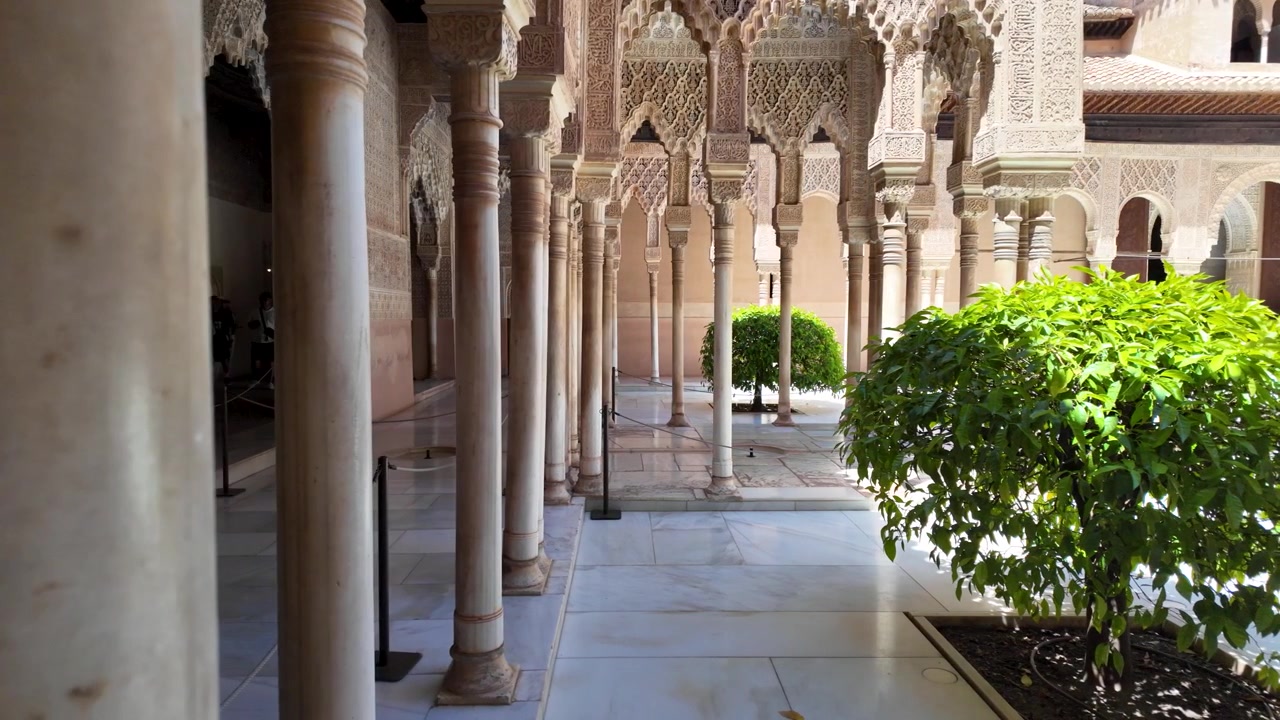 Svelamento al rallentatore da dietro una colonna di marmo che mostra il cortile e l'architettura islamica ornata dei Palazzi Nasridi nell'Alhambra, Granada, Spagna.