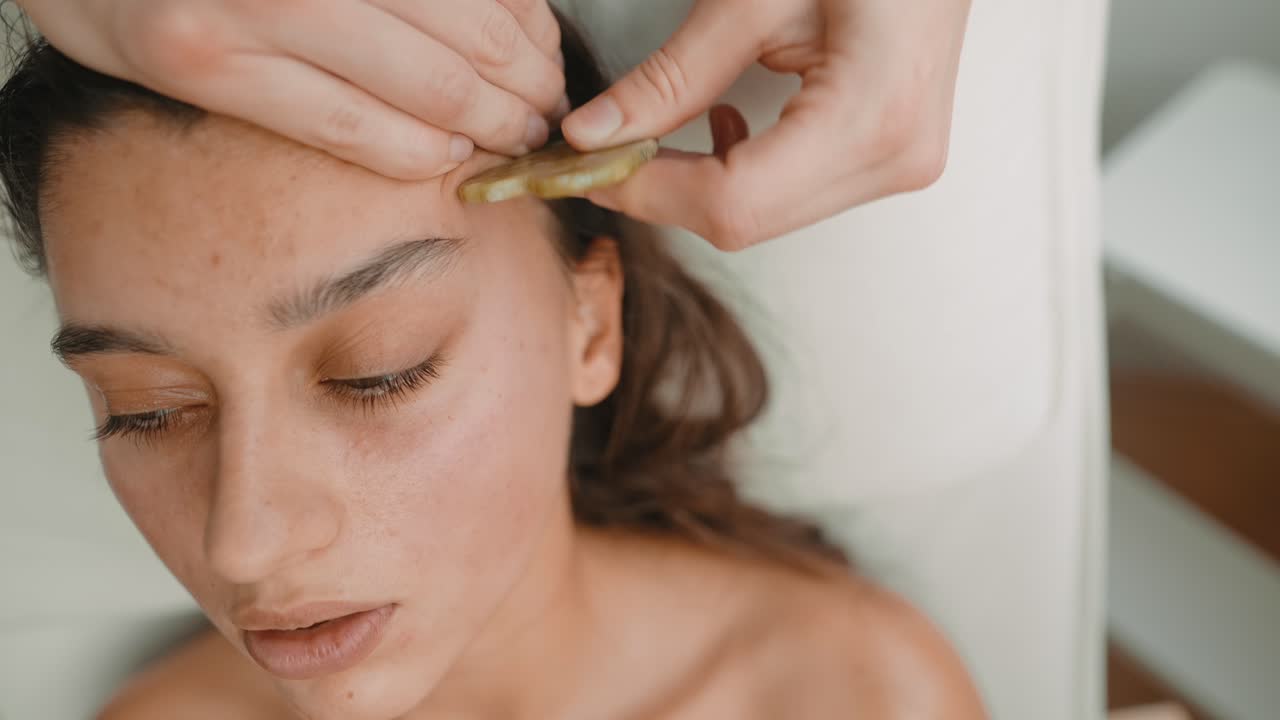 Junge Frau bei Gua Sha Gesichtsbehandlung im Spa