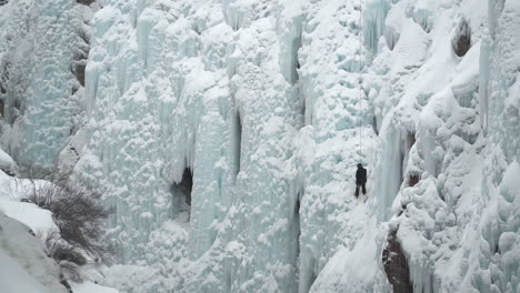 escalador en un acantilado de hielo congelado bajando con una cuerda