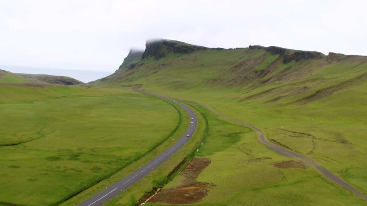 Aerial view of Icelandic road winding through lush green mountains