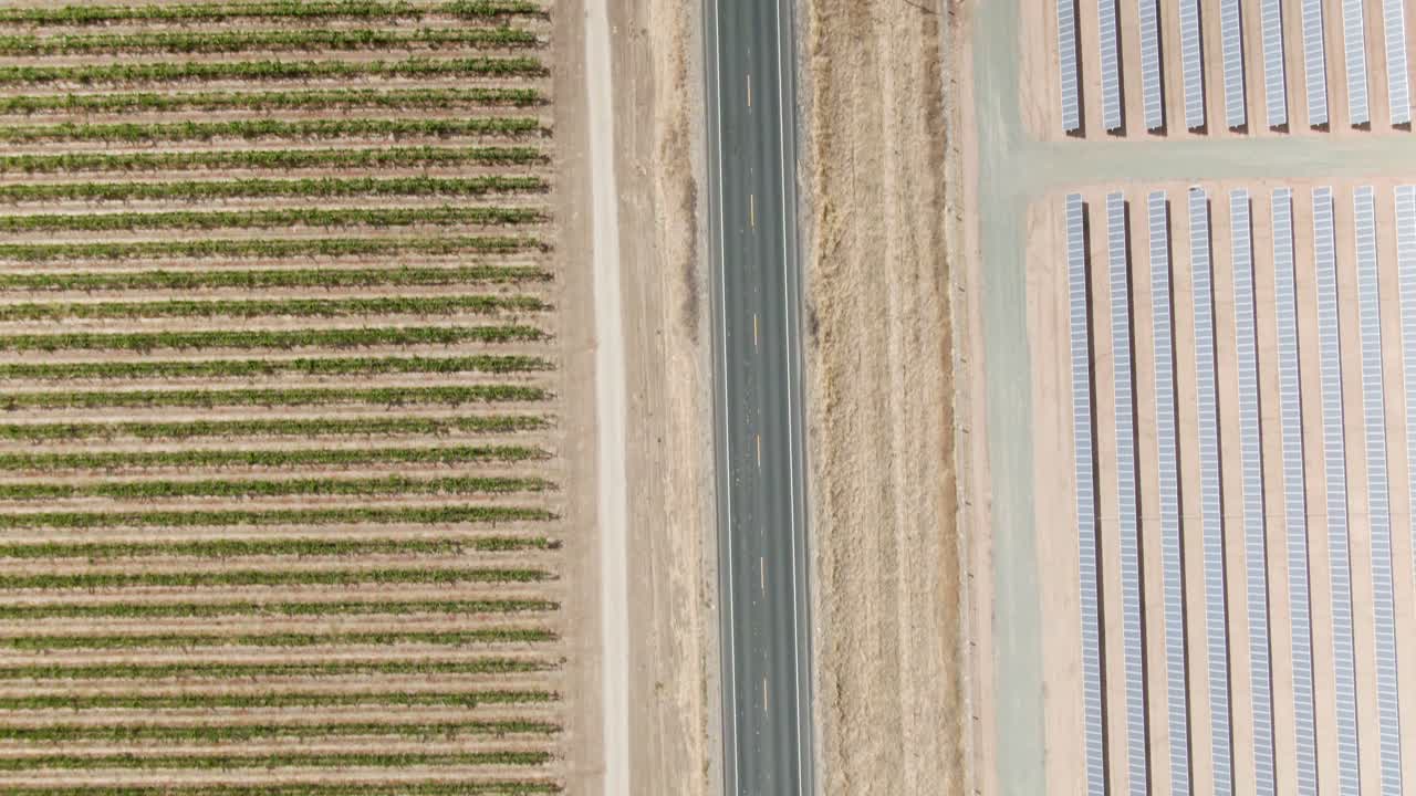 vista de pájaro a gran altitud sobre un camino rural en el campo con paneles solares en el lado derecho y un viñedo en el lado izquierdo