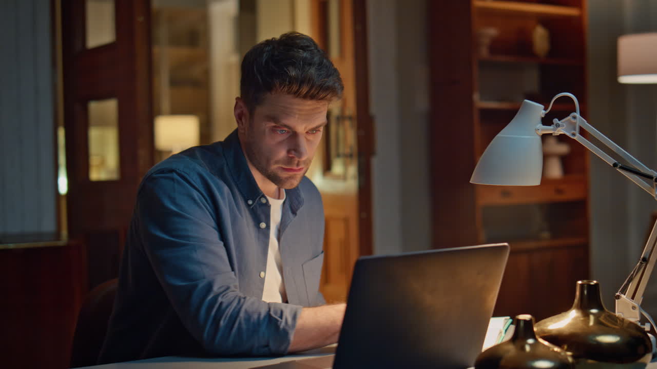 Serious accountant texting laptop night home closeup. Focused man writing notes