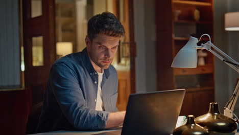 serious accountant texting laptop night home closeup. focused man writing notes