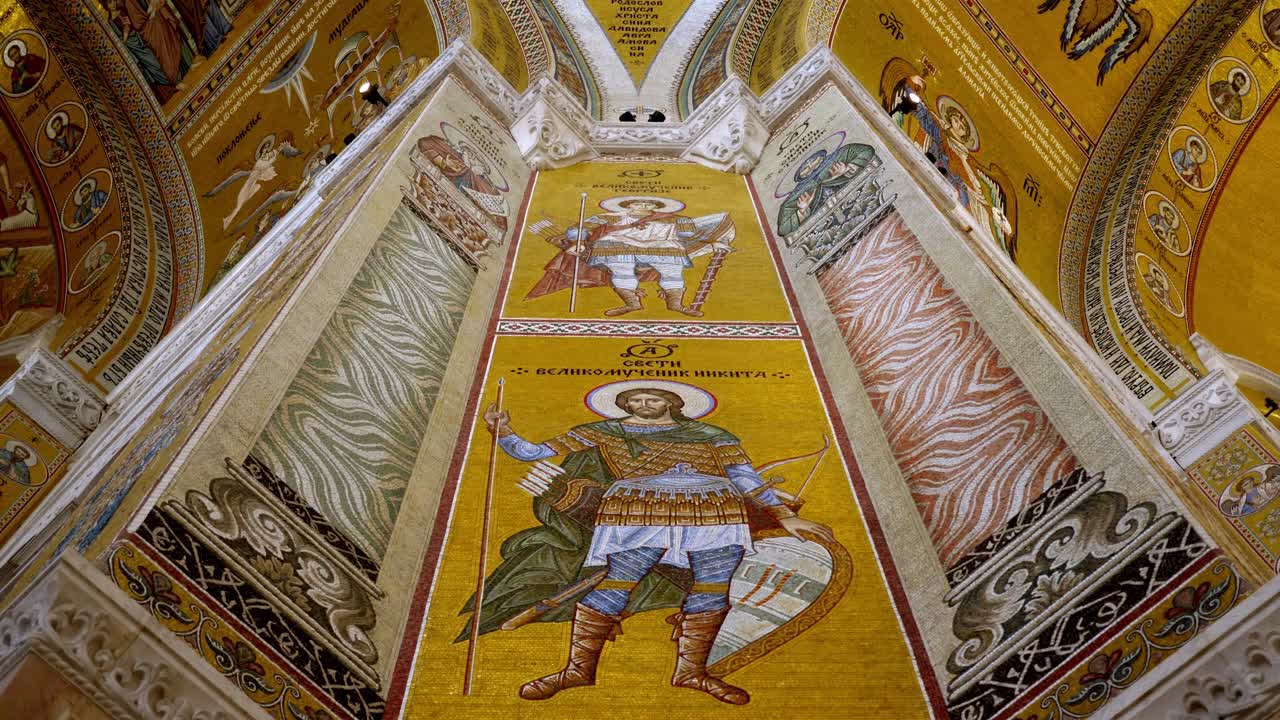 Close-up view of saints painted on a column inside the Temple of Saint Sava in Belgrade, showcasing detailed Orthodox frescoes and rich religious iconography