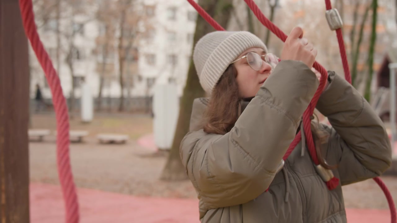 Donna bianca che testa corde rosse, mani in fase di indagine che regolano la presa con espressione concentrata. Piumino e cappello di lana, anelli di corda e raccordi metallici. Scena spontanea di stagione fredda, studio cinematografico tattile.