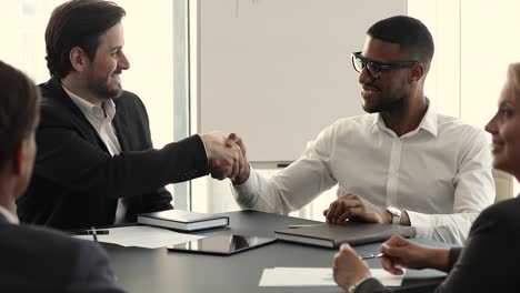 multiethnic business partners succeed goal, finish meeting with handshake gesture