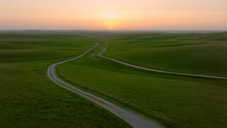 winding road through rolling green hills at sunset