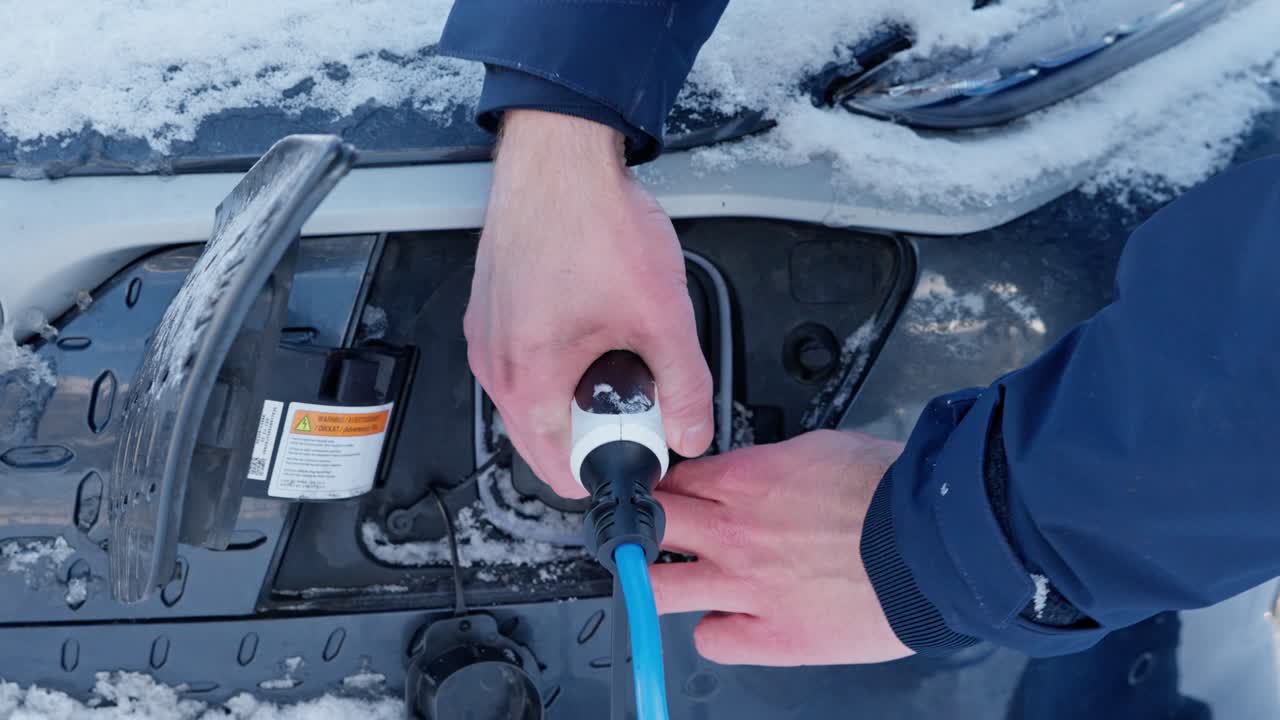 Man tries to remove plug and cable from EV car frozen stuck in charging socket.