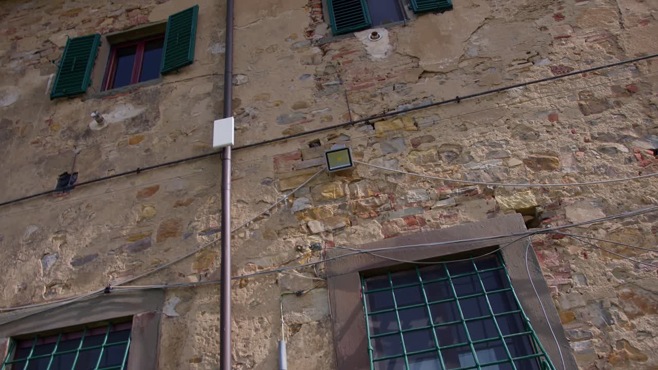 A smooth gimbal shot panning from left to right, showcasing the stone walls and beautiful windows of a historic Tuscany villa