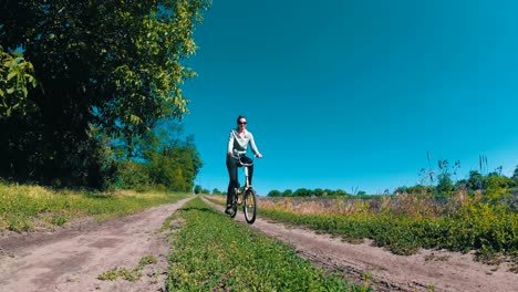 young woman riding vintage bicycle along a rural road in a village