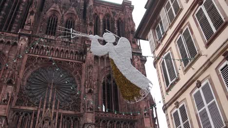 angels decorations floating above city street and in front of cathedral at festive christmas market in strasbourg, france europe