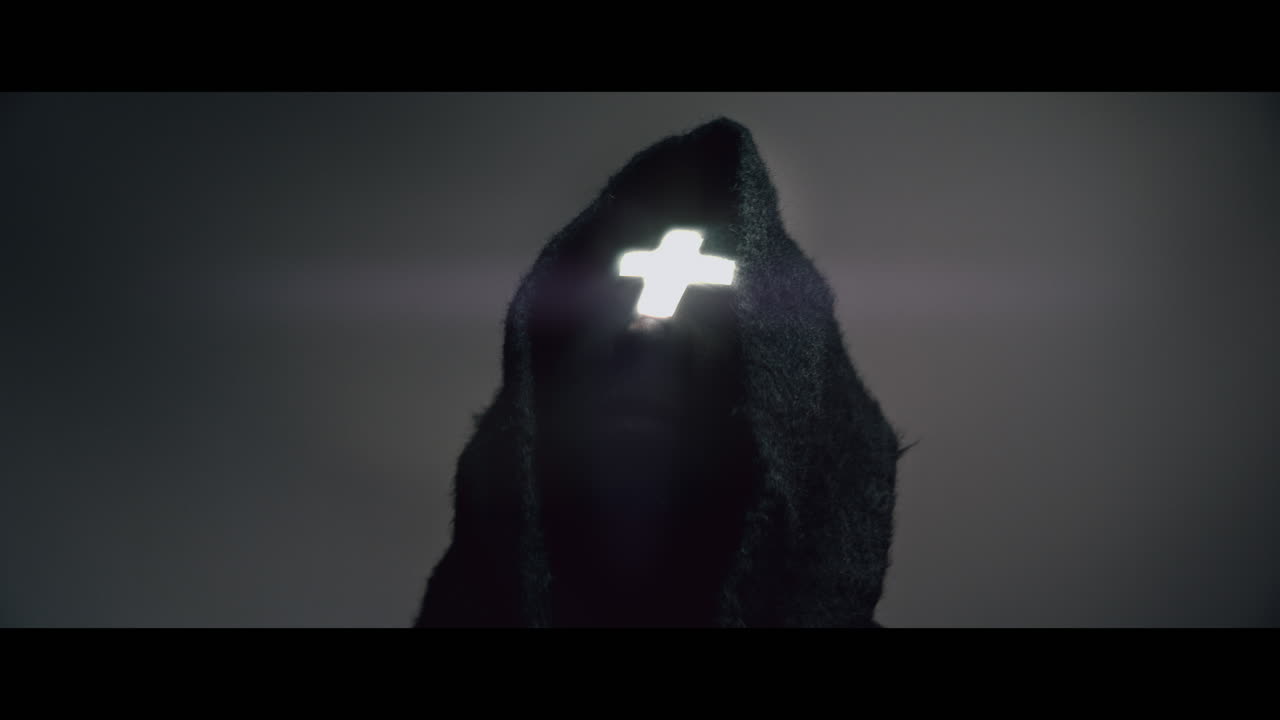 Masked man with cross of light glowing on his face moves his head up