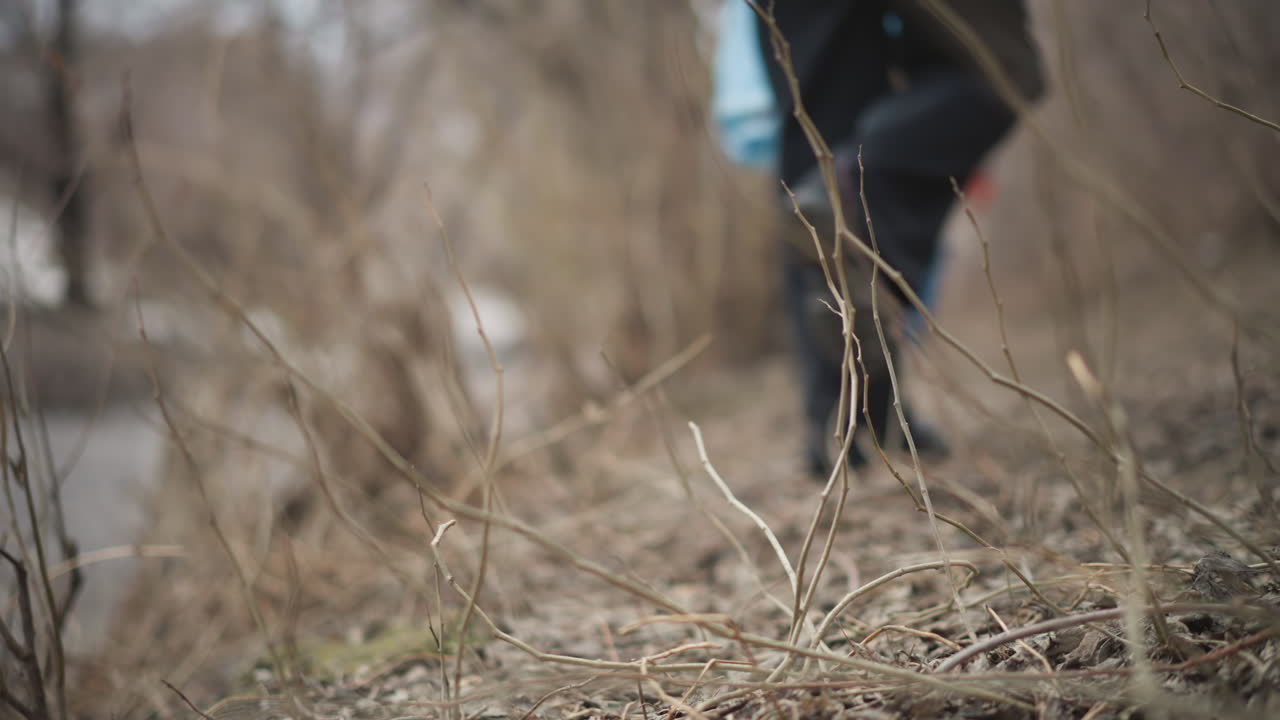 Volunteers in bright safety vests walking along riverbank during environmental cleanup, carrying blue plastic bags filled with collected litter to protect nature, reduce pollution, and support ecological