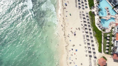 Waves-washing-upon-hotel-resort-beach-with-people-on-summer-holiday