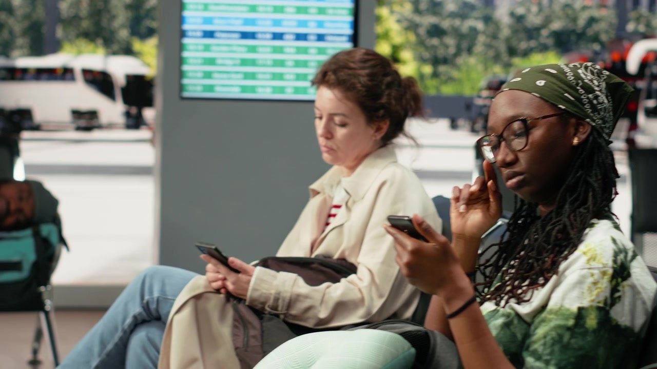 Businessman working on notebook in bus terminal next to passengers waiting