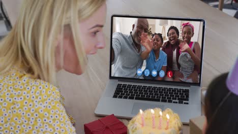 caucasian mother and daughter sitting at table using laptop having birthday video call