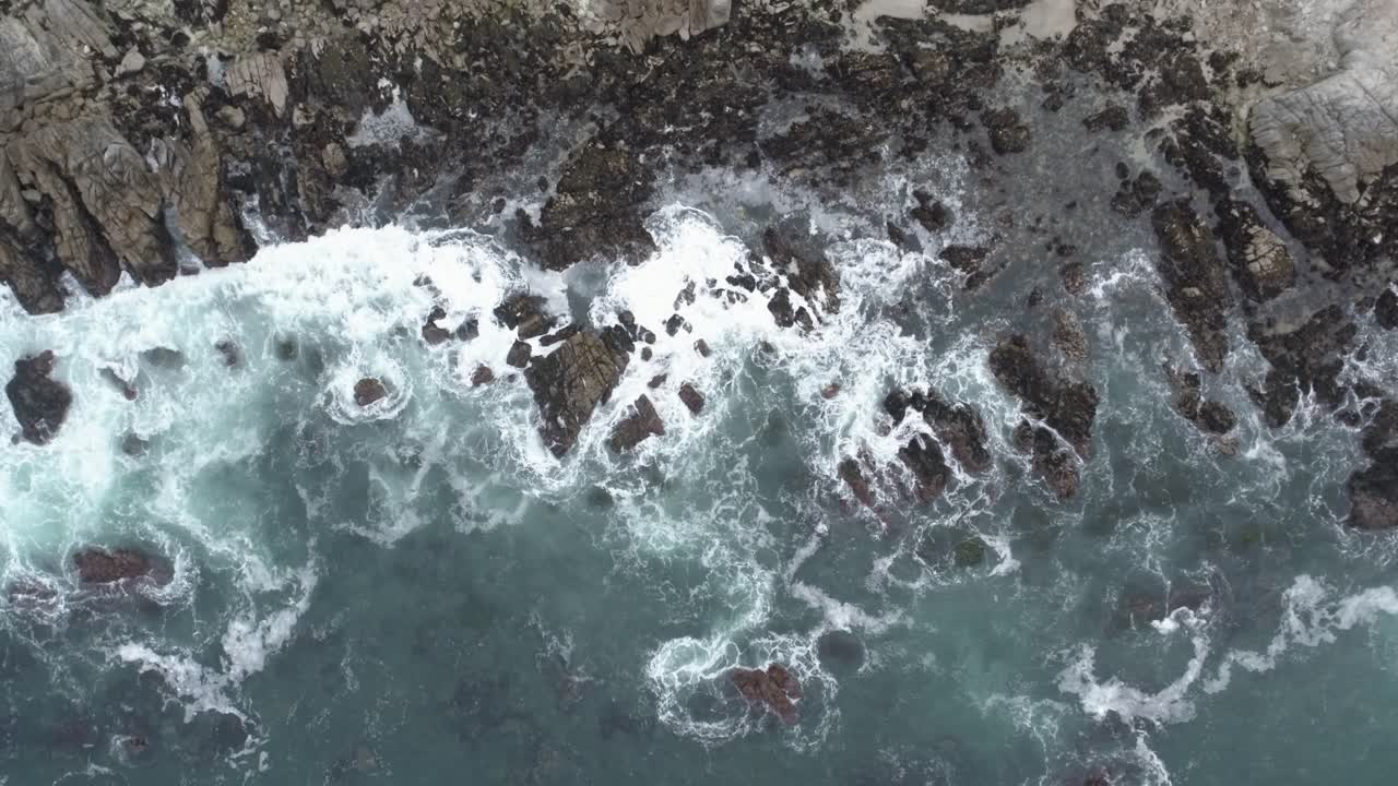 agua de mar áspera golpeando rocas en la bahía de monterey california - girando de arriba hacia abajo