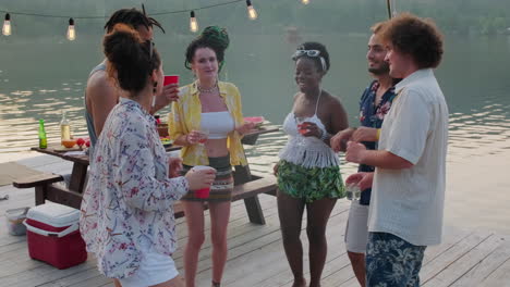 diverse friends dancing on wooden pier at lake party