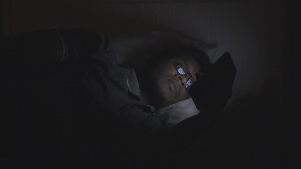 Uomo che usa il telefono a letto di notte