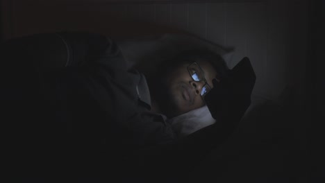 man using phone in bed at night