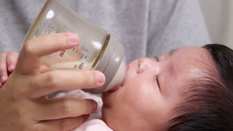 mother feeding her newborn baby some milk as she cradles her child in her arms as its sleeps soundly