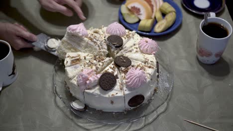 mom puts the children on plates pieces of white birthday cake, which is decorated with pink marshmallows and dark chocolate. the concept of a children's home holiday. close-up. 4k.