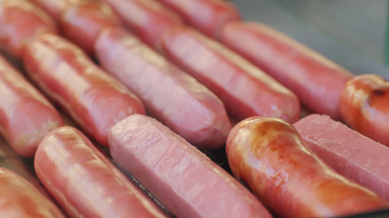 Fried sausage in breadcrumbs on a stick close-up.Cooking corn dogs in boiling oil. Traditional asian corndog snacks street food. Korean Chinese street local market with traditional food. American fast food corndogs with sauce on the top. High quality 4k footage