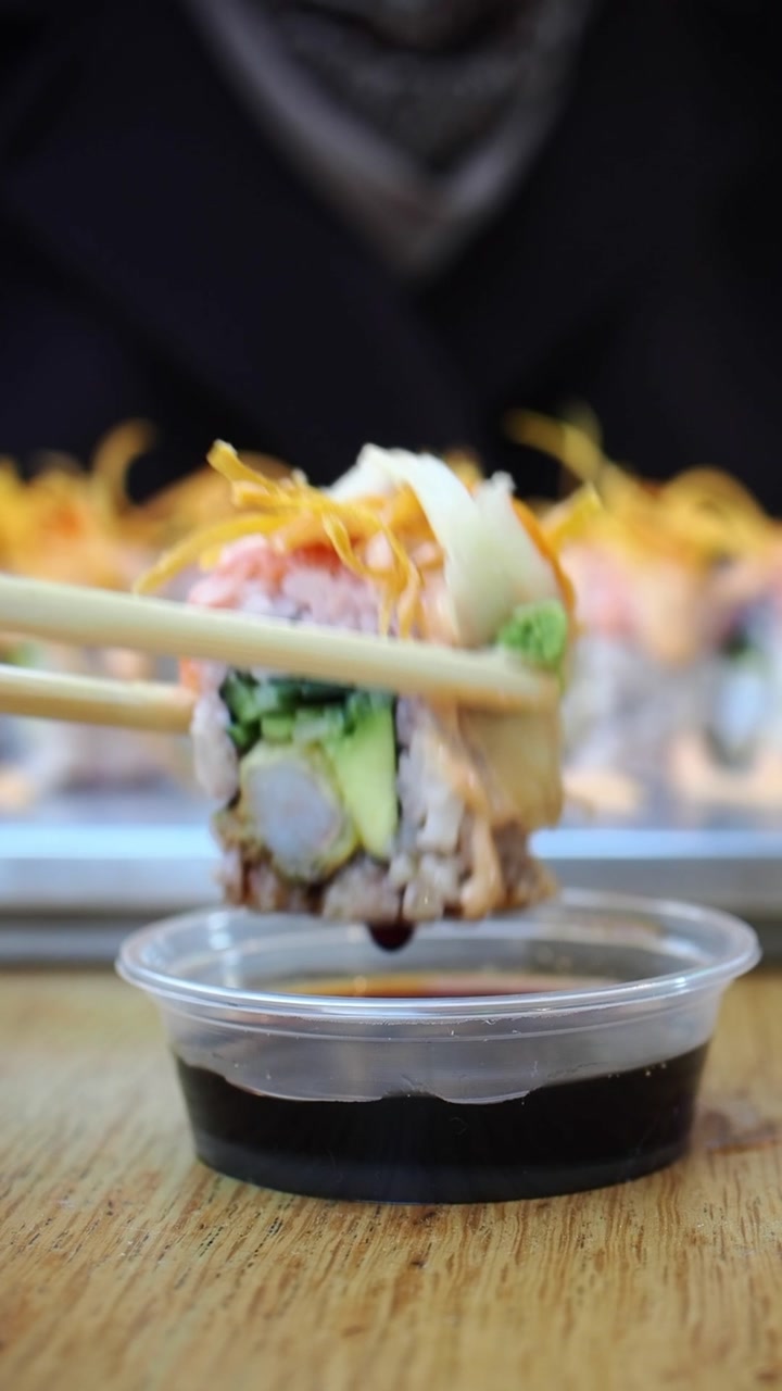 Dipping a Fresh Sushi Roll into Soy Sauce with Chopsticks