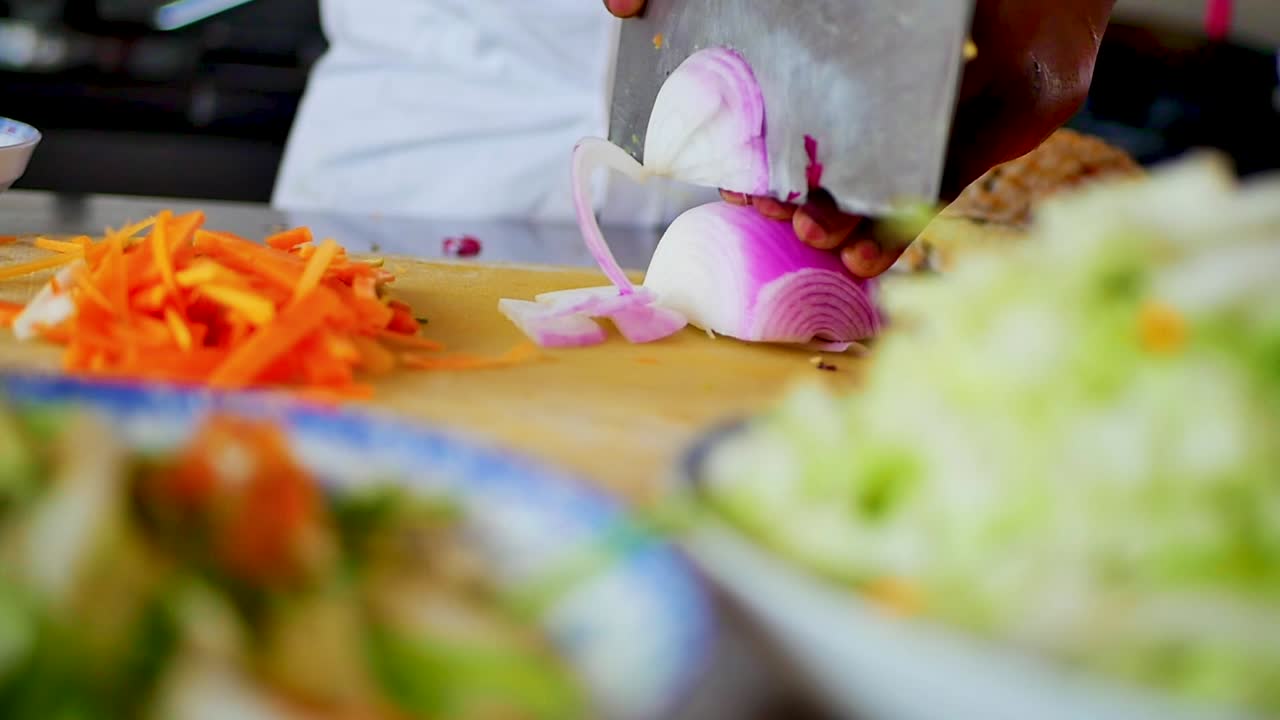 A Chef chopping up Red onions with a large meat clever in hand in slow motion, static shot
