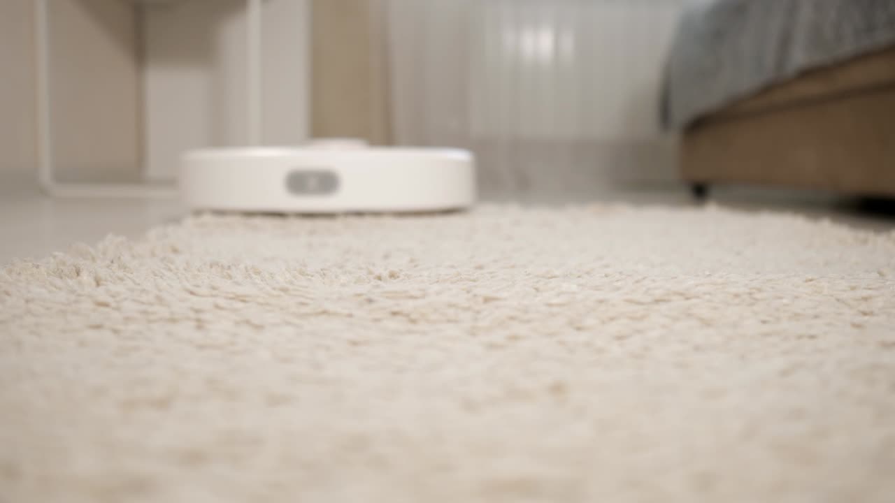 White robot vacuum cleaner cleans long pile carpet close-up