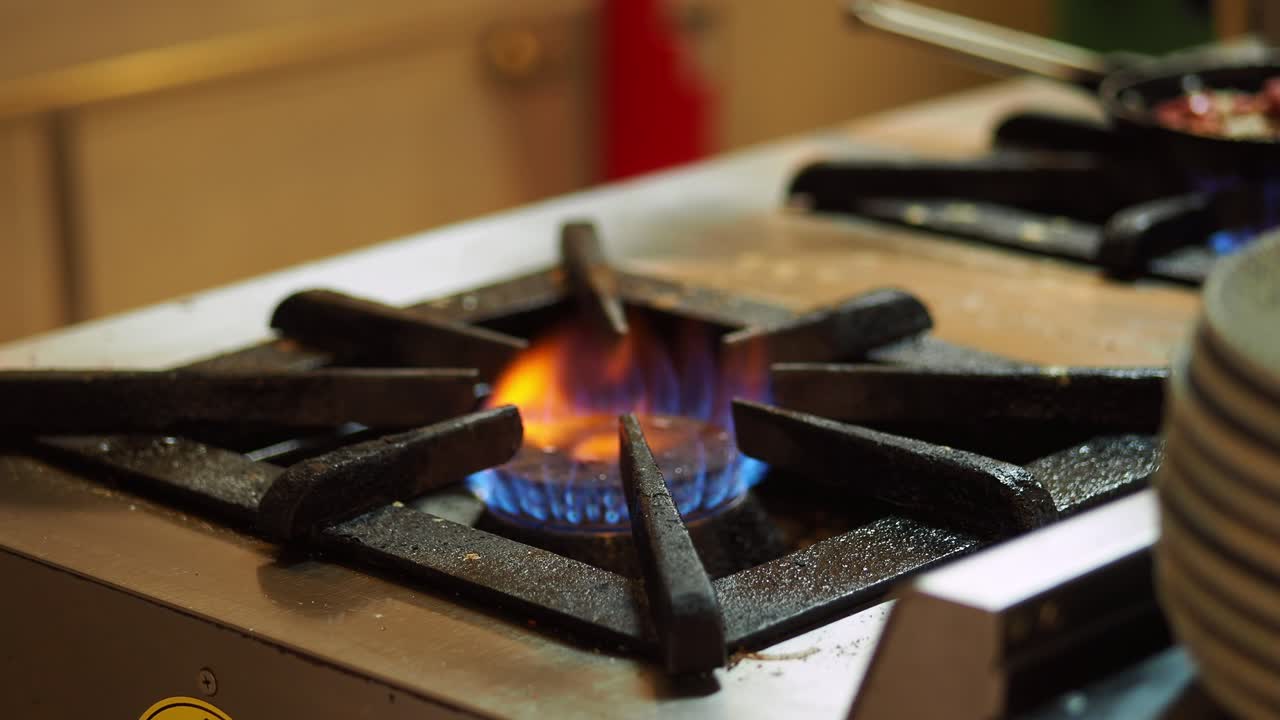 Quemador de estufa de gas con llama azul y naranja en cocina comercial