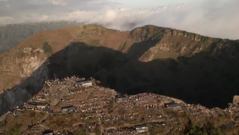 aerial pan: tourists on rim of mount batur volcano crater at sunrise