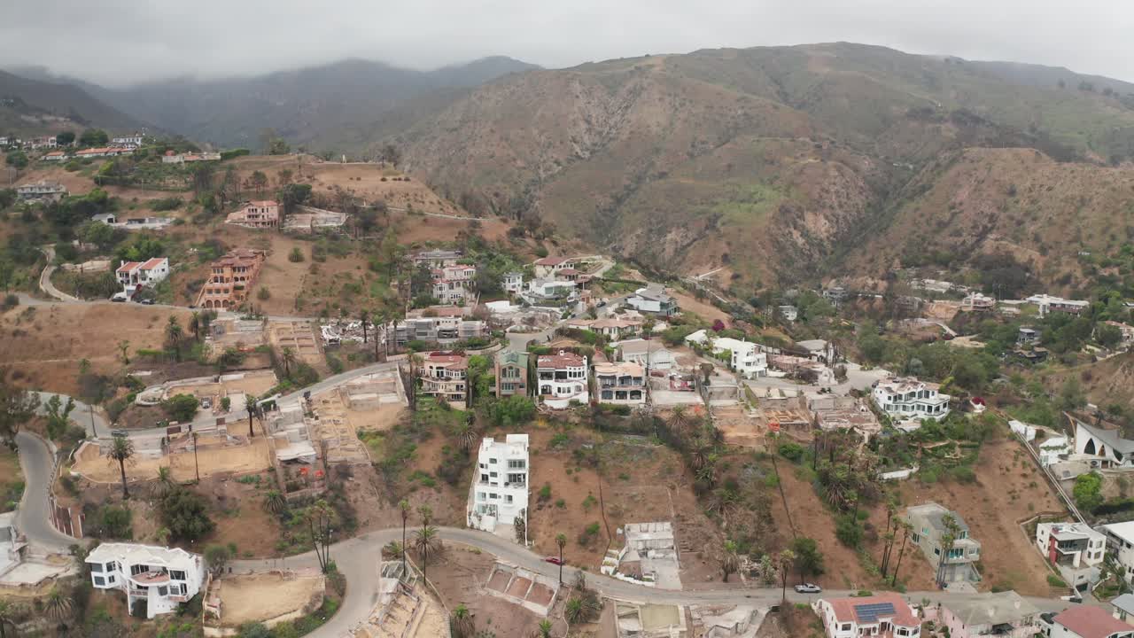 Aerial wide reverse pullback shot of affected properties at Las Flores Canyon after the Palisades Fire in Malibu, California. 4K at 30 FPS