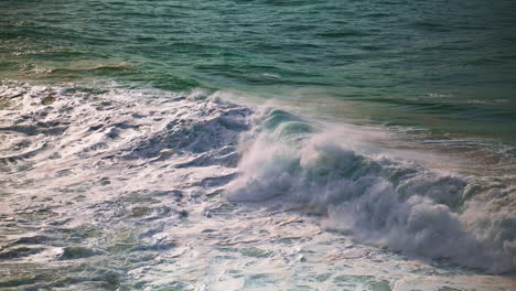 las olas espumosas de la orilla del mar en un día soleado. olas enormes rompiendo la superficie salpicando