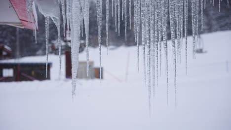 Carámbanos-Que-Crecen-Del-Techo-En-Invierno,-Fondo-Borroso-De-La-Escena-Invernal