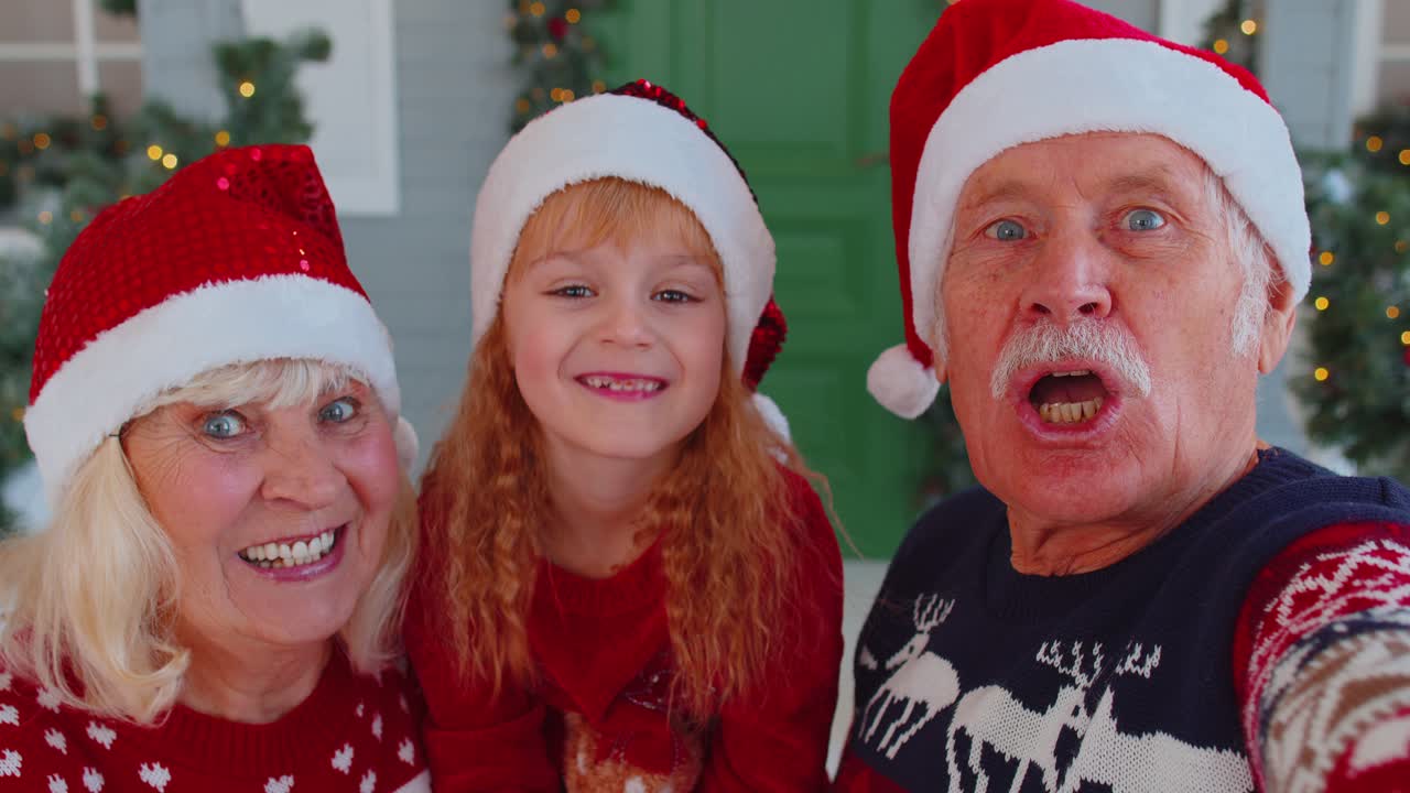 una foto de los abuelos mayores con la nieta y la niña tomando selfies con el teléfono móvil en navidad.