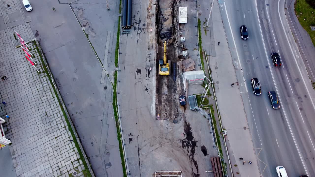 Aerial View of Excavator in Trench Laying Pipeline Next to Road