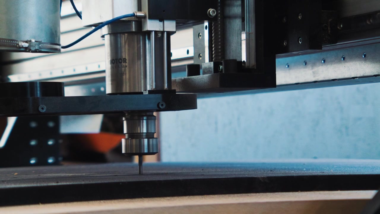 Dettaglio laterale di una testa di macchina CNC che si muove sopra una tavola durante la produzione automatizzata di lavorazione del legno