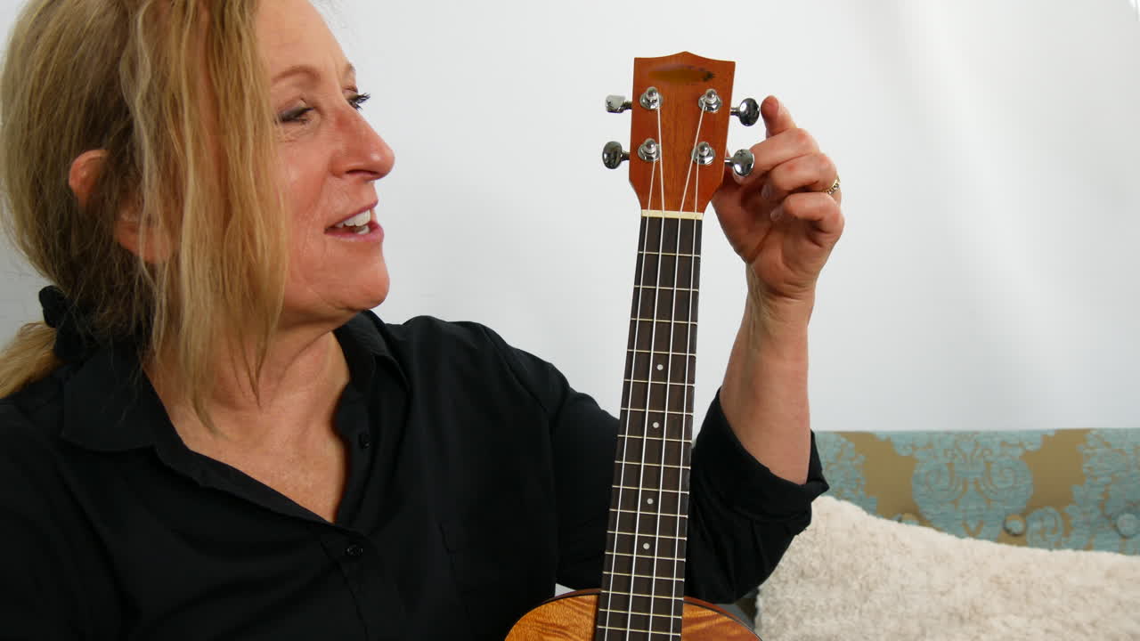 mujer explicando las partes de la guitarra ukelele, sonriente, de mano
