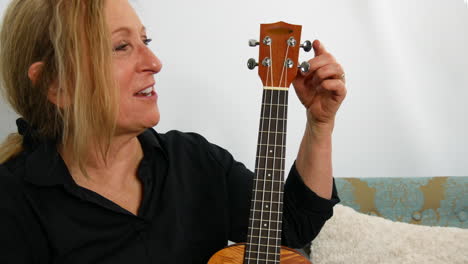 woman explaining the parts of the ukulele guitar, smiling, handheld