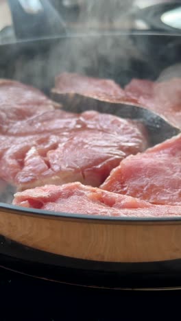 cooking meat or fish in a frying pan with steam